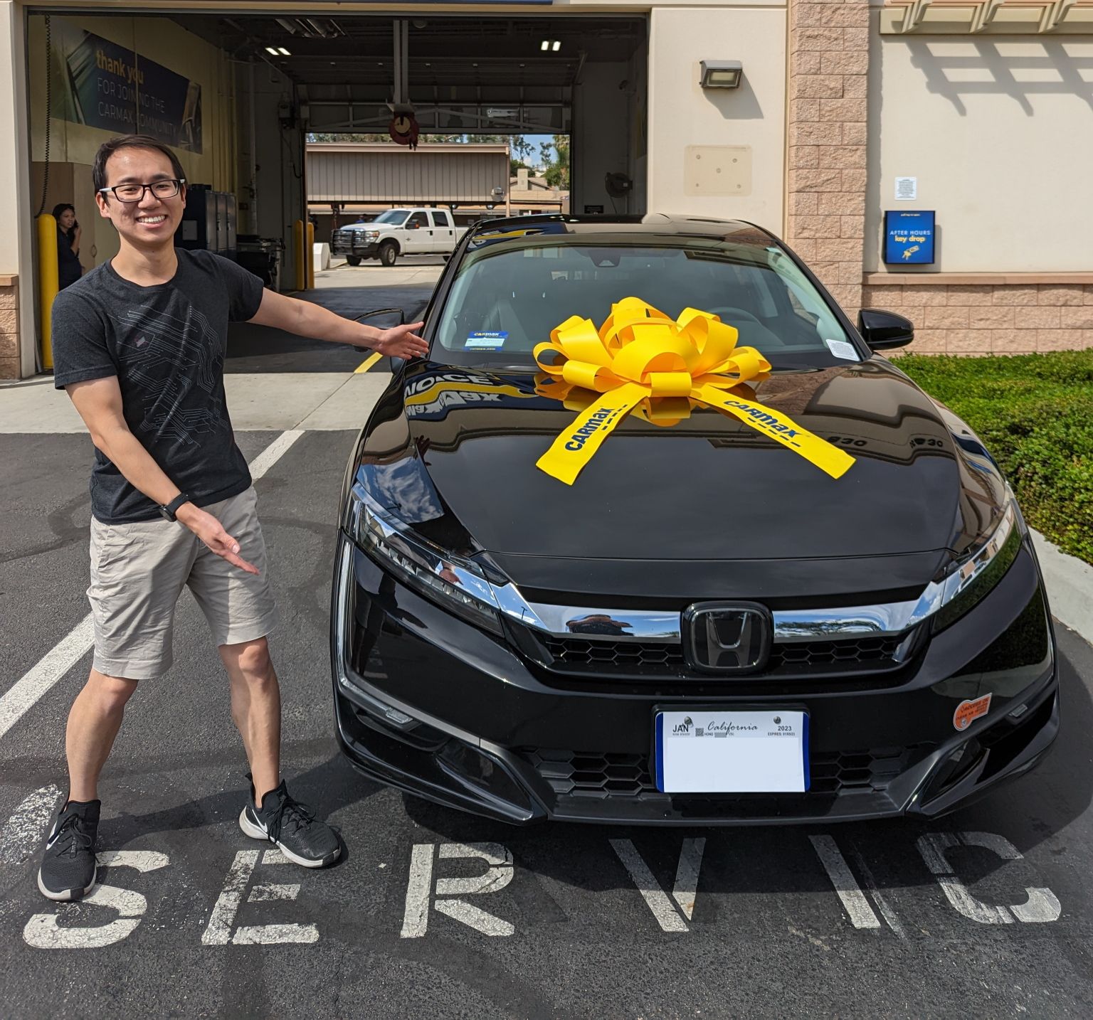 Adam standing next to a Clarity at CarMax with a big yellow bow on the hood
